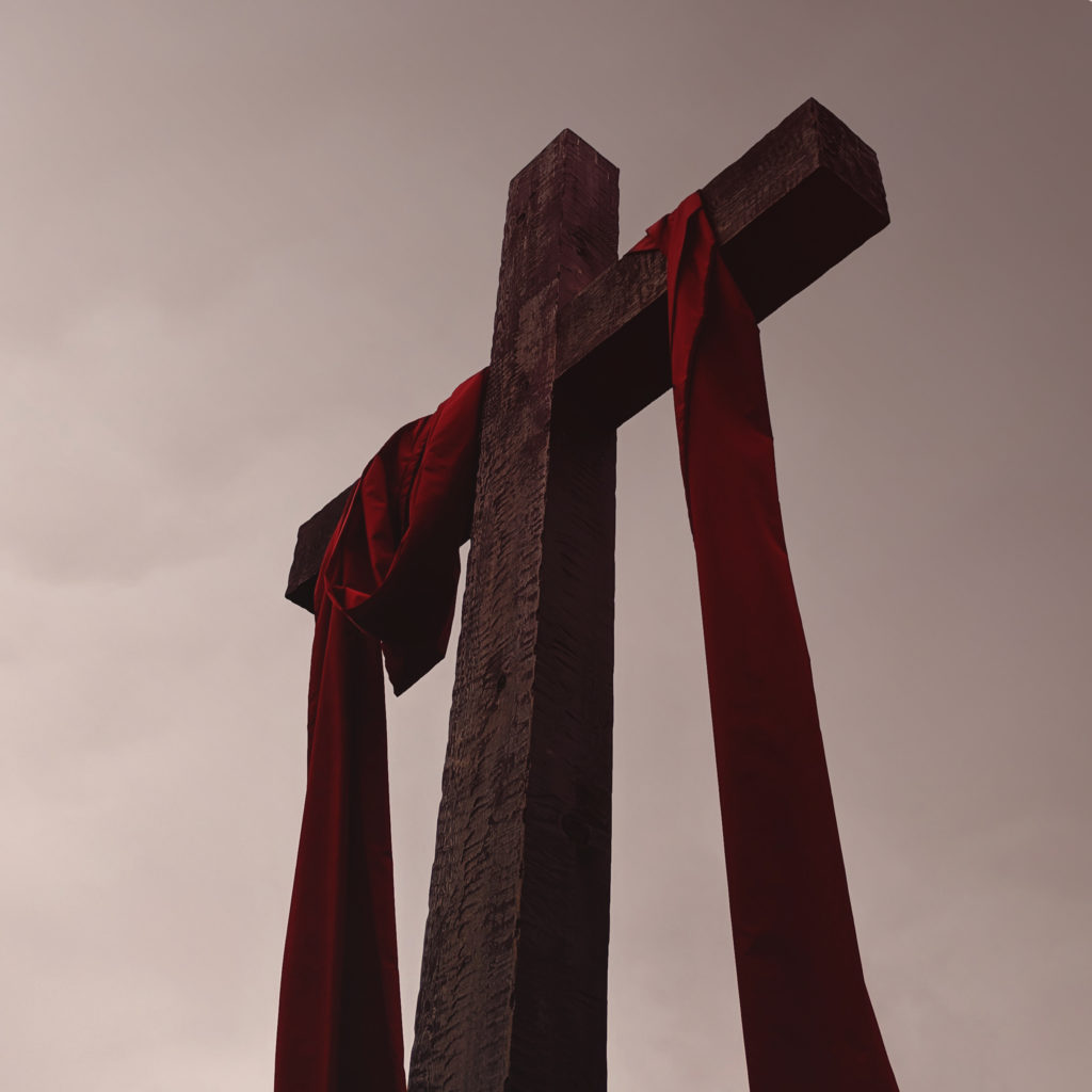 large wooden cross with a dark red cloth draped over its arms
